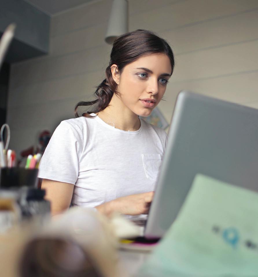 Junge Frau arbeitet mit Laptop an journalistischen Texten